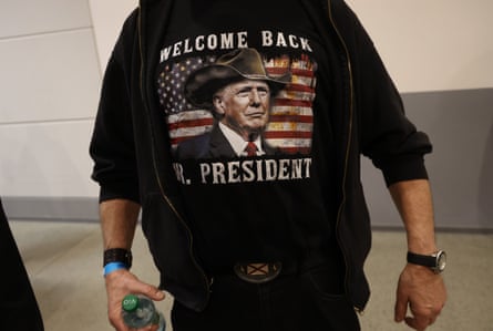 An AfD supporter wears a hoodie printed with a Trump image reading “Welcome Back Mr. President”