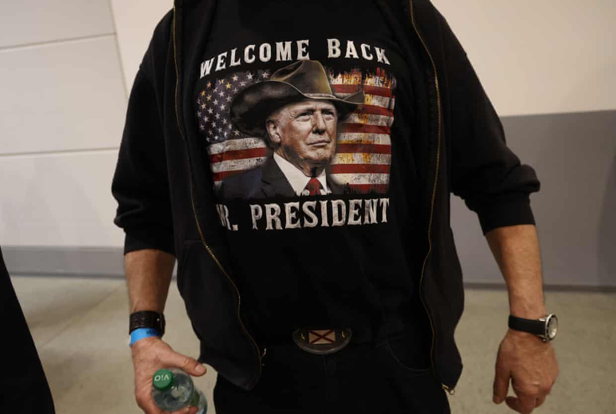 An AfD supporter wears a hoodie printed with a Trump image reading “Welcome Back Mr. President”