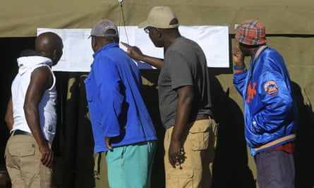 People look at results placed outside a polling station in Harare