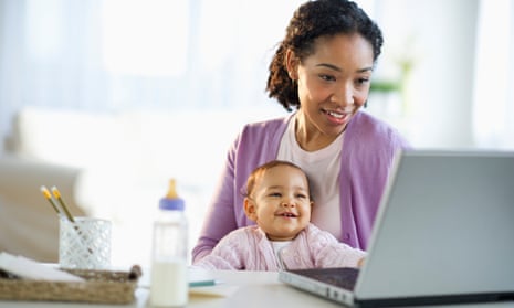 Woman holding baby and using laptop