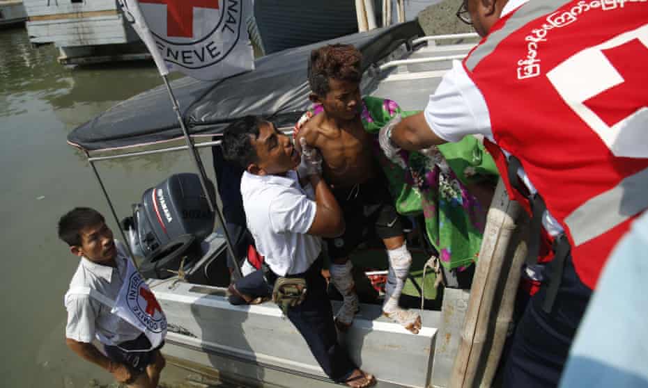 A Myanmar Red Cross worker helping a wounded boy off a boat on 23 March