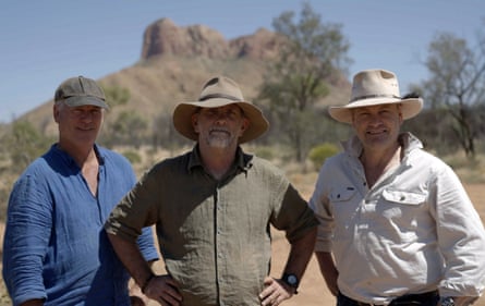 The hunters wear sun hats in front of a mountain
