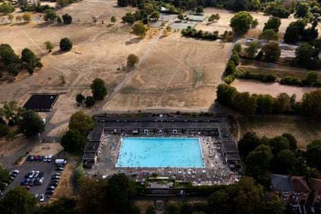 An aerial image of swimmers in a light blue pool bordering dry grassland.
