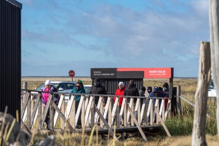 A group of people walk across a bridge in a grassy landscape