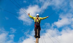 A telecoms engineer repairing lines at the top of a telegraph pole