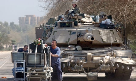 Looters push TVs and other items past a US army vehicle in Baghdad.