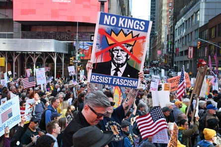 A man in large crowd holds an anti-Trump sign.