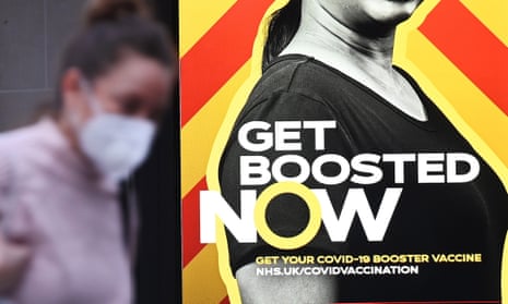 A shopper in London walks past an advert for the government’s Covid-19 booster campaign