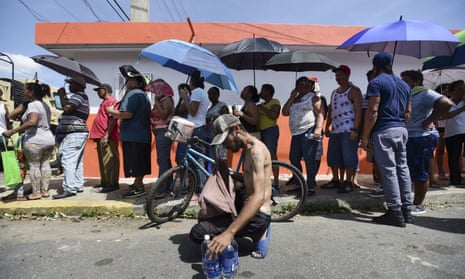 People in San Juan wait in line at Barrio Obrero to receive supplies from the national guard.