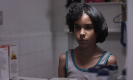 A film still showing a young boy with half straight, half curly afro hair. 