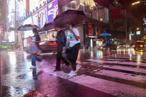 People out in the street during heavy rain from the storm at Times Square in New York City