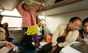 People traveling in a sleeper compartment of a train, China.