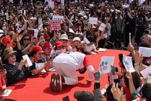 Kim Moon-soo bows deeply on a platform surrounded by supporters