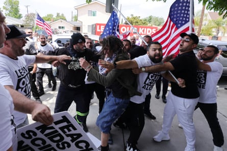 People fight each other in a crowd with an American flag as a backdrop.