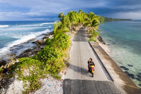 A couple on a motorbike pass through the narrowest point of Fongafale island in the Funafuti atoll