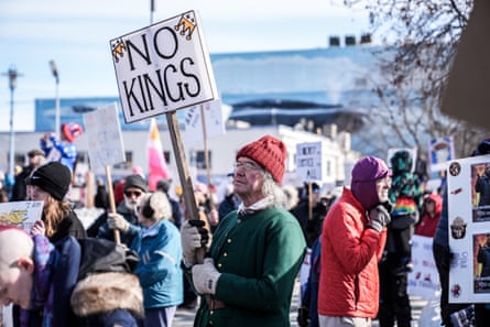 A man in a crowd holds a sign that says ‘No Kings’