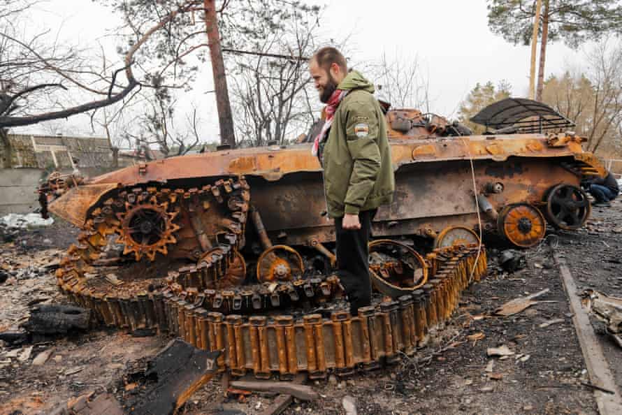 A Ukrainian soldier surveys the wreckage of a destroyed Russian tank at a village near Irpin on the outskirts of Kyiv.