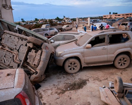 An overturned vehicle rests against a mud-covered one after a tornado struck Marsala, Sicily, Italy