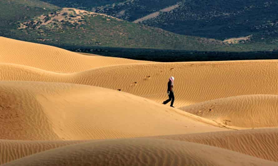 Sand dunes and figure walking across the Maowusu desert.