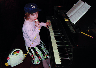 Billie Eilish sitting at a piano as a child