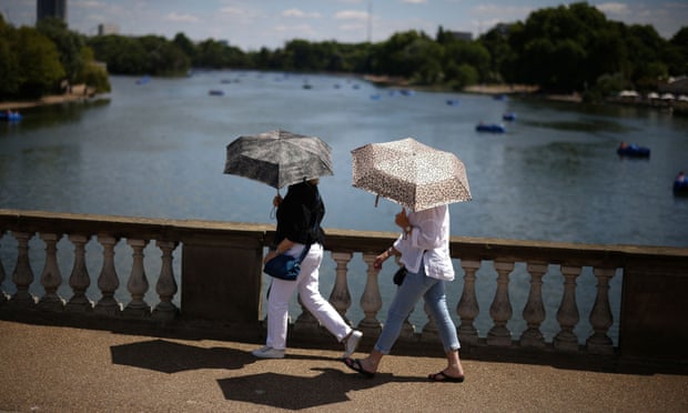 People use umbrellas to shelter from the sun in Hyde Park, London, on Saturday