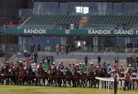 The runners in the Grand National line up for the start in front of empty stands except for a few owners.
