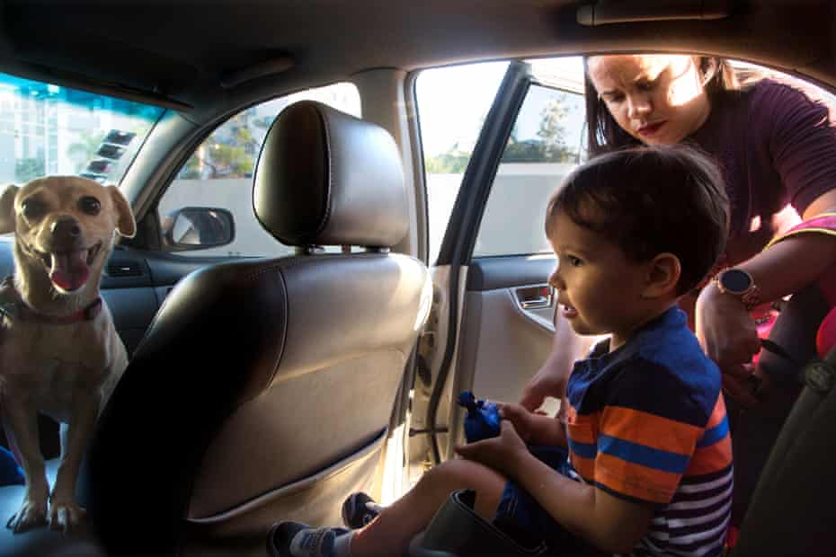 Noah, de 3 años, está amarrado a su asiento de seguridad por su madre Jennipher Mariel Gómez, de 29 años, afuera de su casa en Santiago, República Dominicana.