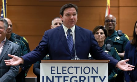 Man arrested at gunpoint in crackdown on DeSantis voter fraud, video shows | Florida 1 desantis behind the podium with the police behind him