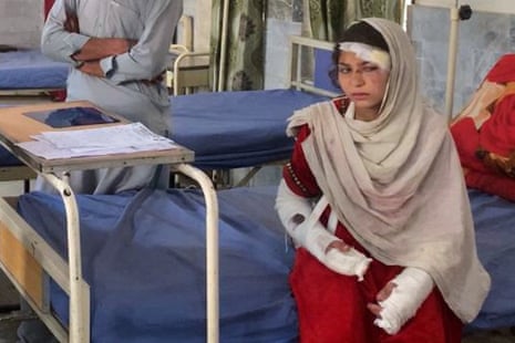 An injured girl with bandaged arms sits on a hospital bed.