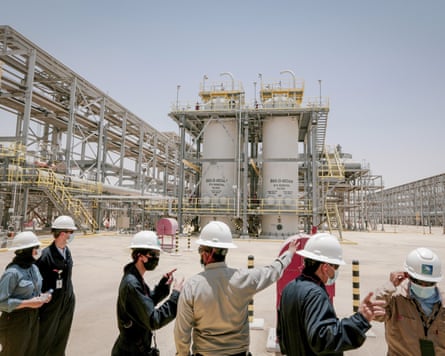 A group of people stand in front of an industrial plant.
