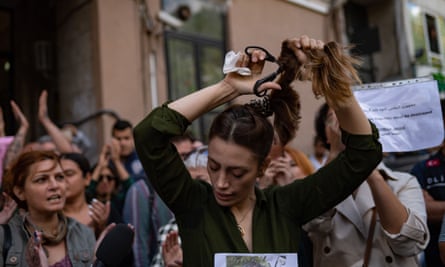 An Iranian woman living in Turkey, cuts her ponytail off during a protest outside the Iranian consulate in Istanbul on 21 September.
