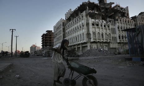 A man walks past a damaged building in Aden, Yemen