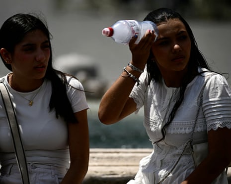 A woman places a bottle filled with ice on her head to cool down at St Peter's Square in the Vatican.