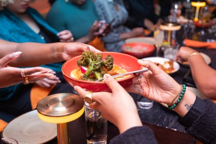 close up of pair of hands passing a dish of food across at a table