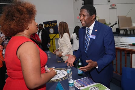 A man in a suit speaks to a woman.