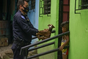 San Salvador, El Salvador. A police officer delivers a puppy to a child