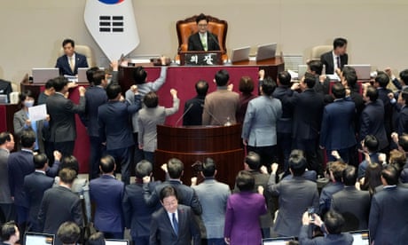 El líder del Partido Democrático de la oposición de Corea del Sur, Lee Jae-myung (abajo en el centro), camina junto a legisladores del gobernante Partido del Poder Popular que protestan contra el presidente de la Asamblea Nacional de Corea del Sur, Woo Won Shik (arriba en el centro), durante una sesión plenaria para la moción de juicio político contra el presidente interino de Corea del Sur, Han Duck-soo, en la Asamblea Nacional en Seúl, Corea del Sur, el viernes 27 de diciembre de 2024. (Foto AP/Ahn Young-joon)