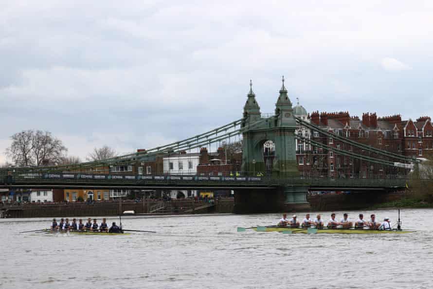 The Oxford boat leads the Cambridge boat under the Hammersmith Bridge.