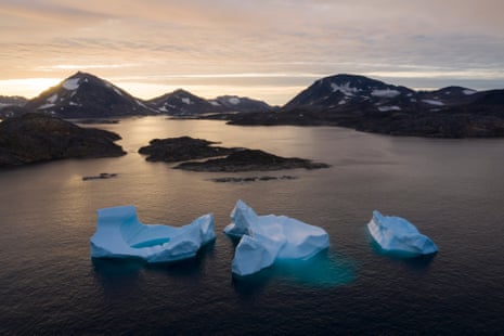 Icebergs in the sea at sunrise, with backdrop of mountains