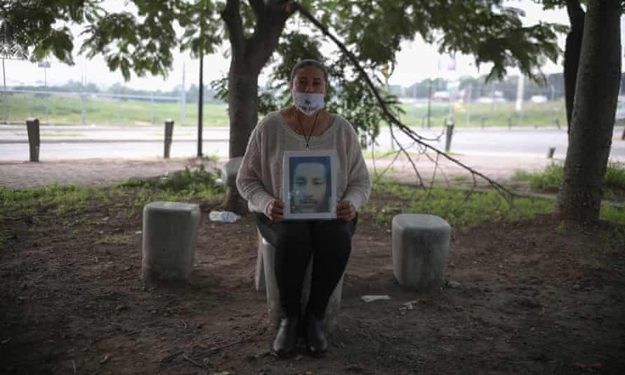 A woman holds a portrait of a missing relative.