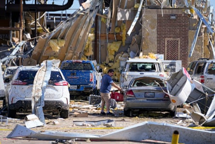 A man looks at a damaged car after a tornado hit on Saturday, in Valley View, Texas.