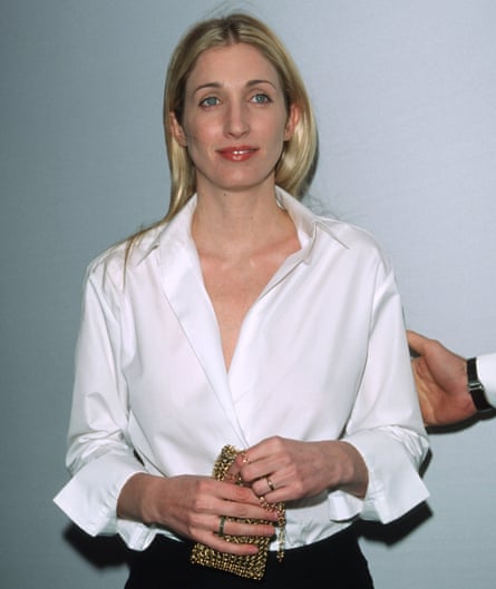 Carolyn Bessette-Kennedy in a white shirt holding a gold bag