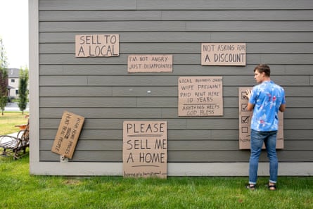 A man hangs signs on the outside of a home.