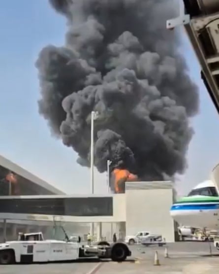 Black smoke billows into a blue sky above a building