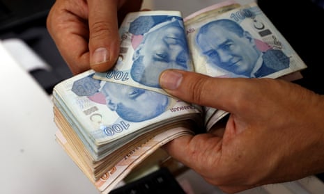 A money changer counts Turkish lira banknotes at a currency exchange office in Istanbul.