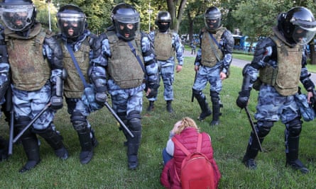 Riot police move past a young woman in Ilyinsky Park on Saturday.