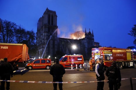 French firefighters try to extinguish a fire as flames are burning the roof of the Notre Dame Cathedral in Paris.