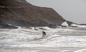 Surfers make the most of the huge waves that crash into the shore at Langland Bay near Swansea.