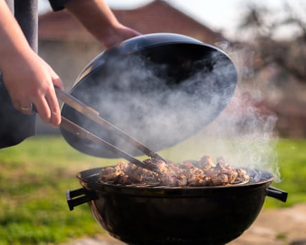 Woman hands in shot while grilling barbecue meet on the grill outdoors in the back yard.