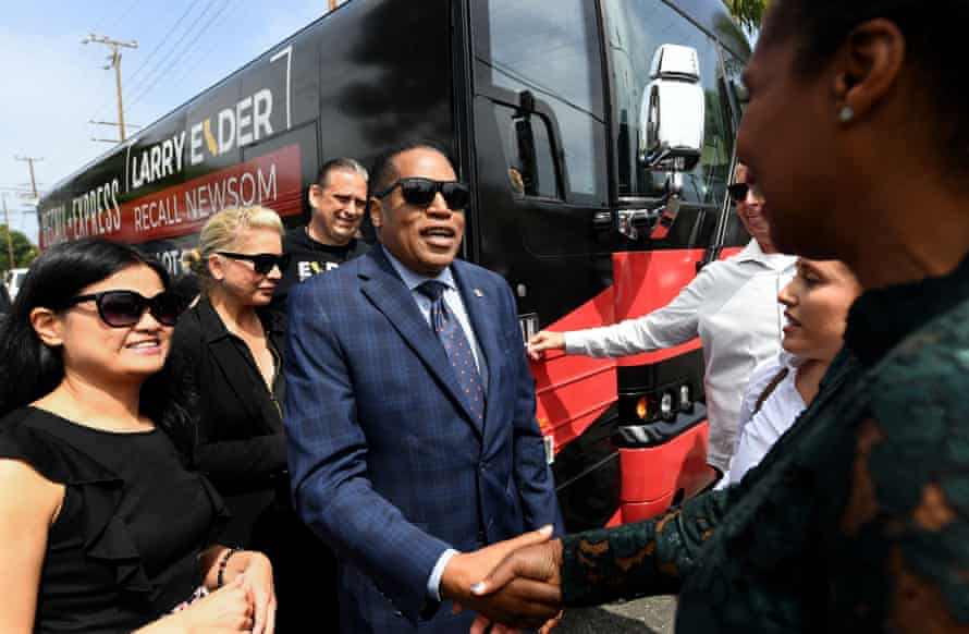 Elder shakes hands with people near campaign bus